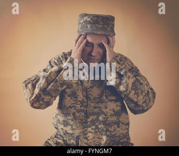 A stressed army man is holding his hands to his head on an  isolated background for a war effect or pain concept Stock Photo