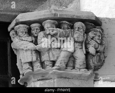 Mono image of architectural detail showing an old man pointing and other traders behind with different expressions and trades Stock Photo