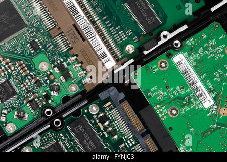 Hard Disk Drive Circuitry Close-Up | STUDIO — Several hard disk drives lie side by side in this overhead macro shot, their circuit boards, barcode labels, and gold-plated SATA connectors exposed for close inspection. Markings from manufacturers including Foxconn and Samsung identify individual memory chips and controllers, illustrating the layered engineering inside a computer's primary storage hardware. Stock Photo