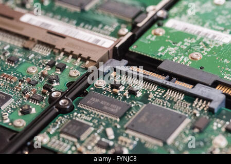 Hard Disk Drive Circuitry Close-up | STUDIO — Macro detail of internal hard disk drive circuit boards reveals densely packed microchips, resistors, and a SATA connector on the underside of the drives. The printed circuit board manages data read and write operations before relaying information to a computer's motherboard. Stock Photo