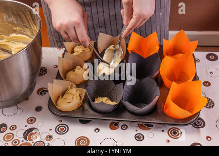 Womans Hands making delicious homemade Cupcakes, filling the forms Stock Photo