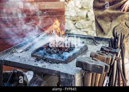 Artistic blacksmith works in the historic blacksmith workshop. Horseshoe for good luck. Manufactory theme. Art production. Stock Photo