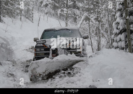 A truck with snowplough on a mountain road in the snow. Stock Photo