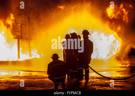 Firefighters spraying down burning structure Stock Photo