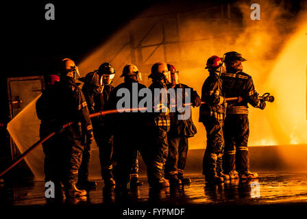 Group of firefighters fighting a burning fire Stock Photo