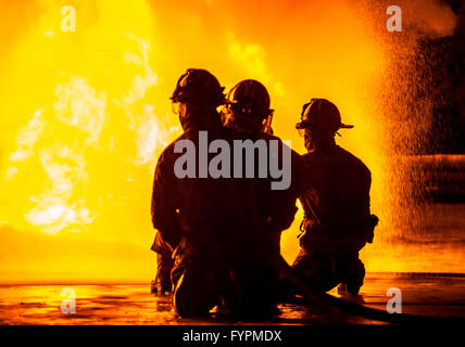 Three firefighters kneeling in front of fire