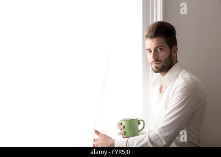 A young man standing at the window Stock Photo