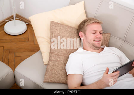 Young man with a Tablet PC on the Sofa Stock Photo