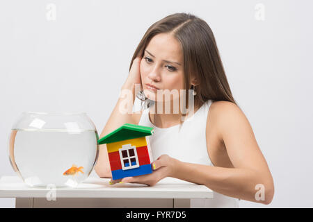 She knocks on the wall of the house a toy aquarium with goldfish Stock Photo