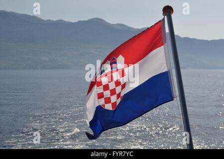 Croatian national flag flying at windy day with adriatic sea in background Stock Photo
