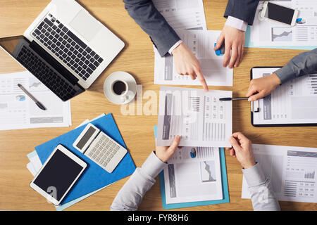 Business people brainstorming at office desk, they are analyzing financial reports and pointing out financial data on a sheet, t Stock Photo