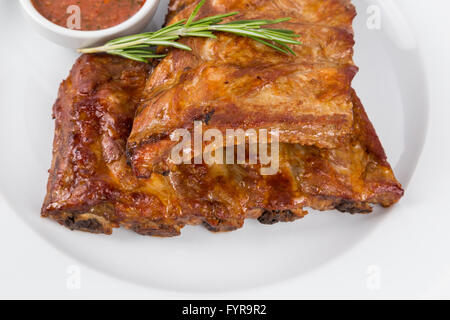 portion hot smoked barbecue ribs on white plate serving in restaurant Stock Photo
