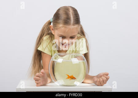Happy six year old girl looking down on the aquarium with goldfish Stock Photo