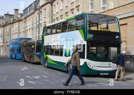 2 men crossing the road in front of Stagecoach Electric Hybrid bus in Magdalen Street East, Oxford city centre. Stock Photo