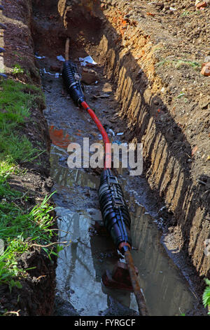 A very large trench dug at the side of a road around a high voltage cable with a new section added between connector blocks. Stock Photo