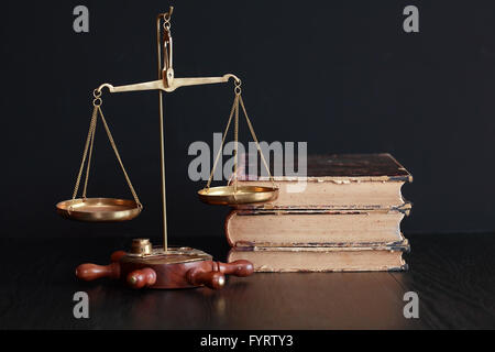 Old brass weight scale near books on black background Stock Photo