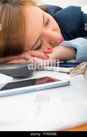 Office woman bent over white desk resting or sleeping with computer keyboard, glasses and mobile spread out Stock Photo