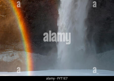 Rainbow in spray of Seljalandsfoss, 66 m high waterfall situated on the river Seljalandsá in winter, Rangárþing eystra, Iceland Stock Photo