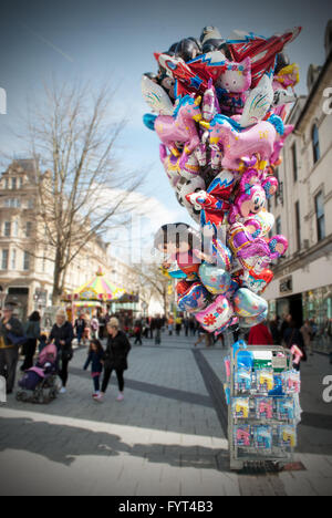 A sunny but wintery high street in Cardiff where a street seller's balloon cart is left unattended. Stock Photo