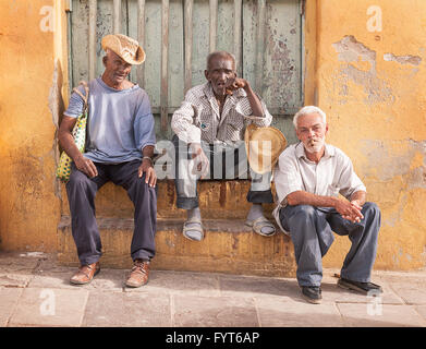 The Three Amigos. Three men sitting together on a doorstep in Trinidad, Cuba. They seem to be old retired friends passing the time in the sunshine. Stock Photo