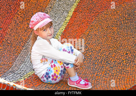 Little girl sitting on the big mosaic panel Stock Photo