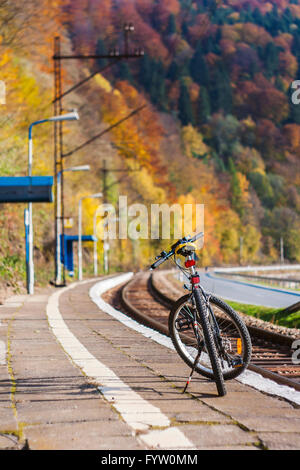 Bicycle standing alone on the railway platform among the autumn forest in Wierchomla, Poland Stock Photo