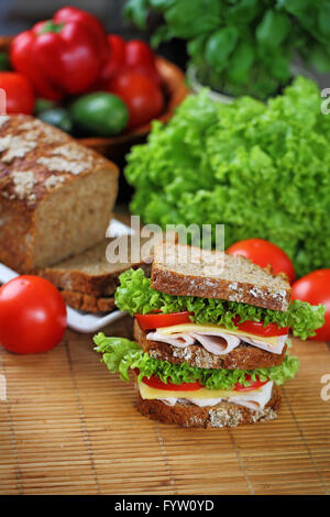 Double sandwich with brown bread, ham, lettuce, tomato, cheese. Stock Photo