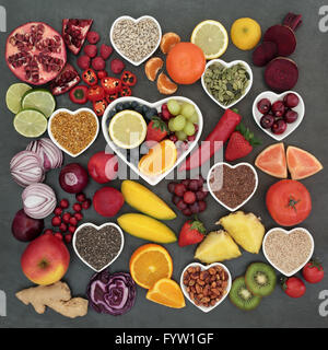 Paleolithic diet health and super food of fruit, vegetables, nuts and seeds in heart shaped bowls on slate background. Stock Photo