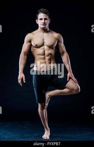 Young strong athlete is making yoga on black background Stock Photo