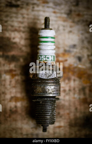 Color image of a used spark plug on a wooden background. Stock Photo