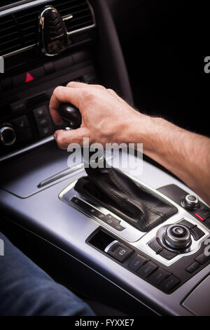 Detail of a hand pulling an automatic gear shifter in a new car. Stock Photo