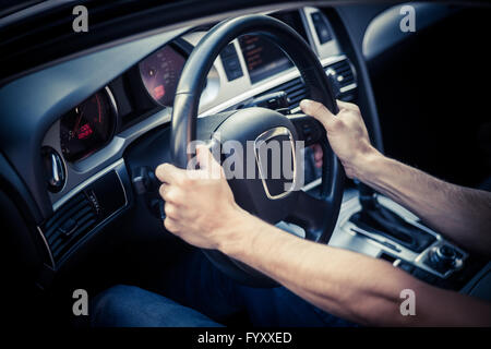 Color image of two hands holding a steering wheel inside a car. Stock Photo