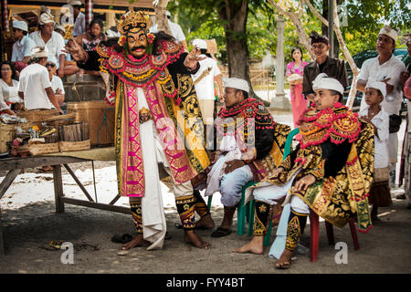 A Balinese actor performing in the open air at a temple ceremony with other mask actors waiting their turn Stock Photo