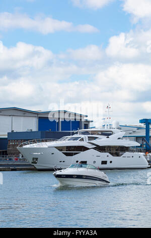 Larson motor boat Fleaky  cruising past Sunseeker luxury boats at Sunseeker yard at Poole in April Stock Photo