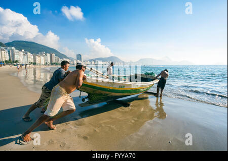 RIO DE JANEIRO - APRIL 4, 2016: Brazilian fishermen launch a brightly painted fishing boat on Copacabana Beach. Stock Photo