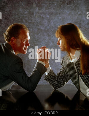 Two work colleagues doing a competitive arm wrestle, indoors. Stock Photo