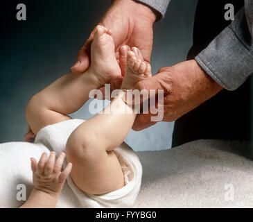 Baby feet being held by father figure, inside. Stock Photo