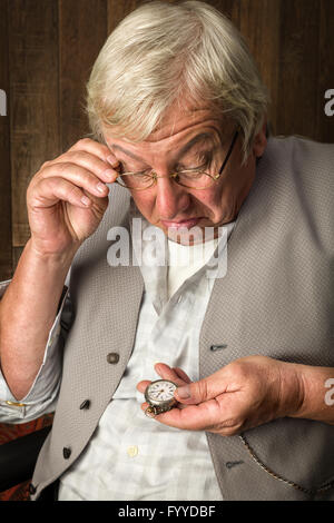 Elderly man checking the time on his antique pocket watch Stock Photo