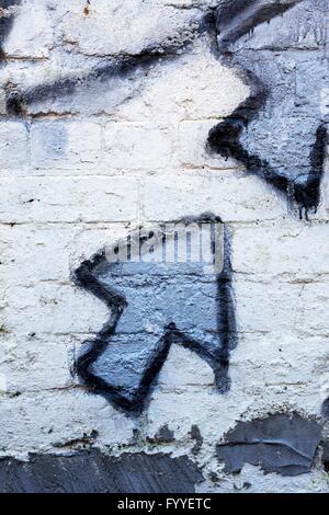 Blue graffiti arrow on a whitewashed brick wall Stock Photo