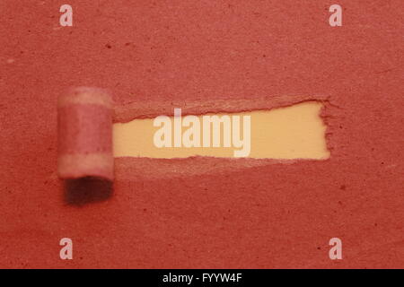 a tear in the middle of the red paper background in yellow Stock Photo