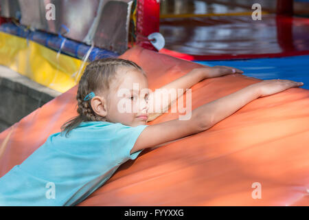 Six-year girl lies on a soft mat in front of the childrens room Stock Photo