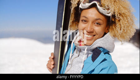Thoughtful young woman standing holding her skis Stock Photo