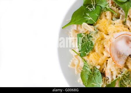 Farfalle pasta with ham, mushrooms, fresh spinach and cheese. Empty space on left side. Stock Photo