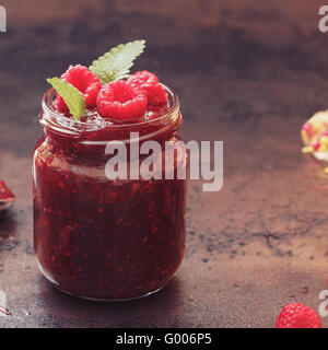 Raspberry jam, close up. A jar of raspberry jam and fresh raspberries on top Stock Photo