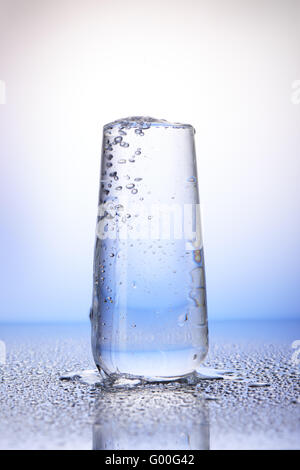 Full drinking glass with reflection in drops of water on white and blue background Stock Photo