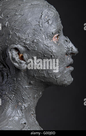 Statuesque woman in wet clay. Woman covered in wet clay. Spa treatment or scary Halloween mask? Stock Photo