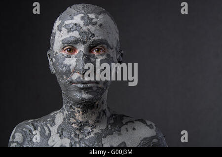 Statuesque woman in wet clay. Woman covered in wet clay. Spa treatment or scary Halloween mask? Stock Photo