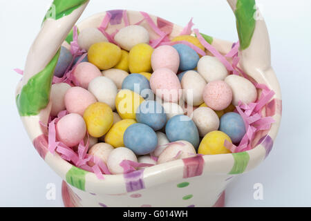 Candy covered Easter eggs in a ceramic basket Stock Photo