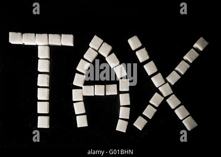 Word TAX made of white refined sugar cubes on black slate background, symbolising sugar tax Stock Photo