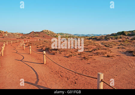 Menorca: red sand on the path to Cala Pregonda, secluded cove with rocks, a landscape looking like the planet of Mars Stock Photo